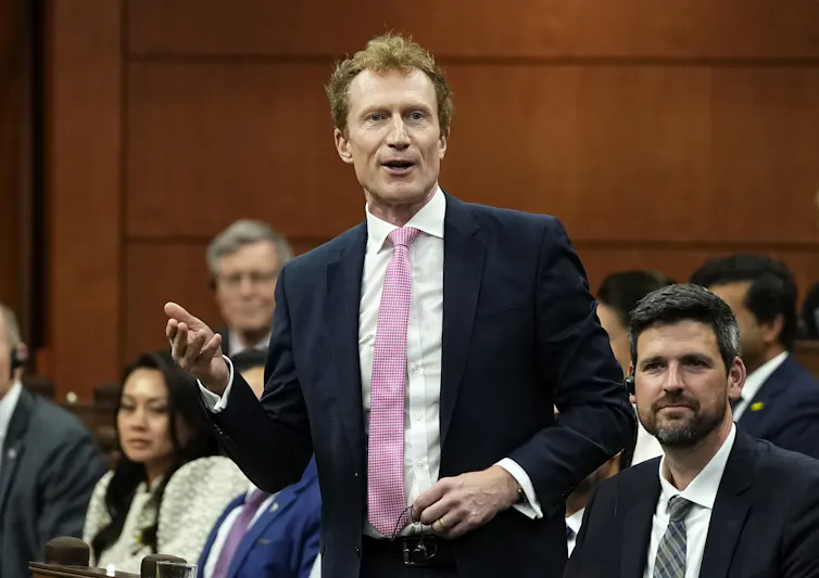 Minister Marc Miller addresses the House of Commons, standing and surrounded by colleagues