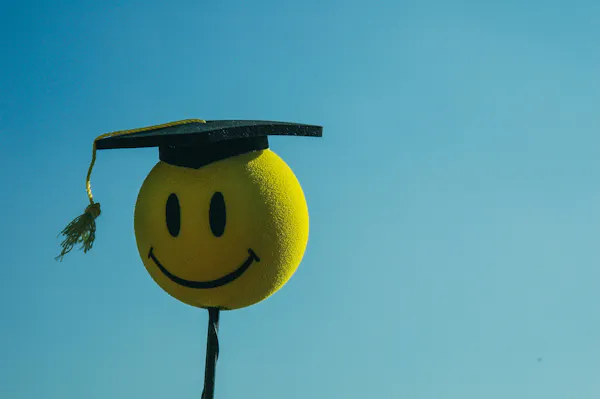 A happy face emoji in a graduate cap.
