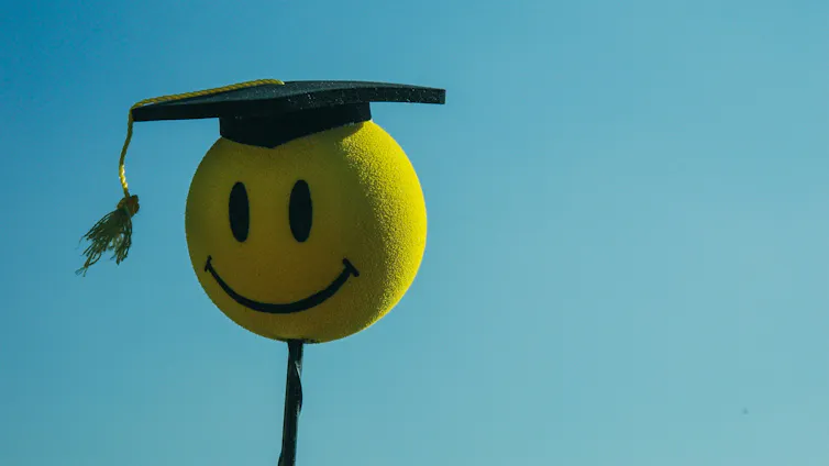 Una cara feliz con un emoji de birrete de graduación.