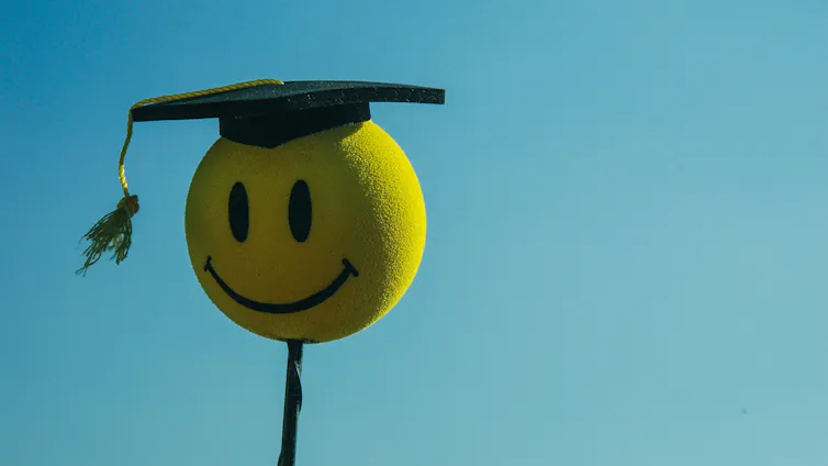 A happy face emoji in a graduate cap.
