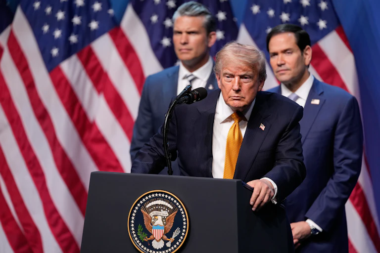 Donald Trump stands at lectern bearing presidential seal with Pete Hegseth, Marco Rubio and US flags behind him