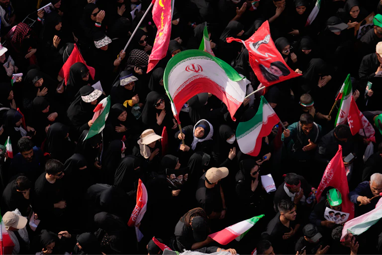 A woman waves a large Iranian flag in a dense crowd