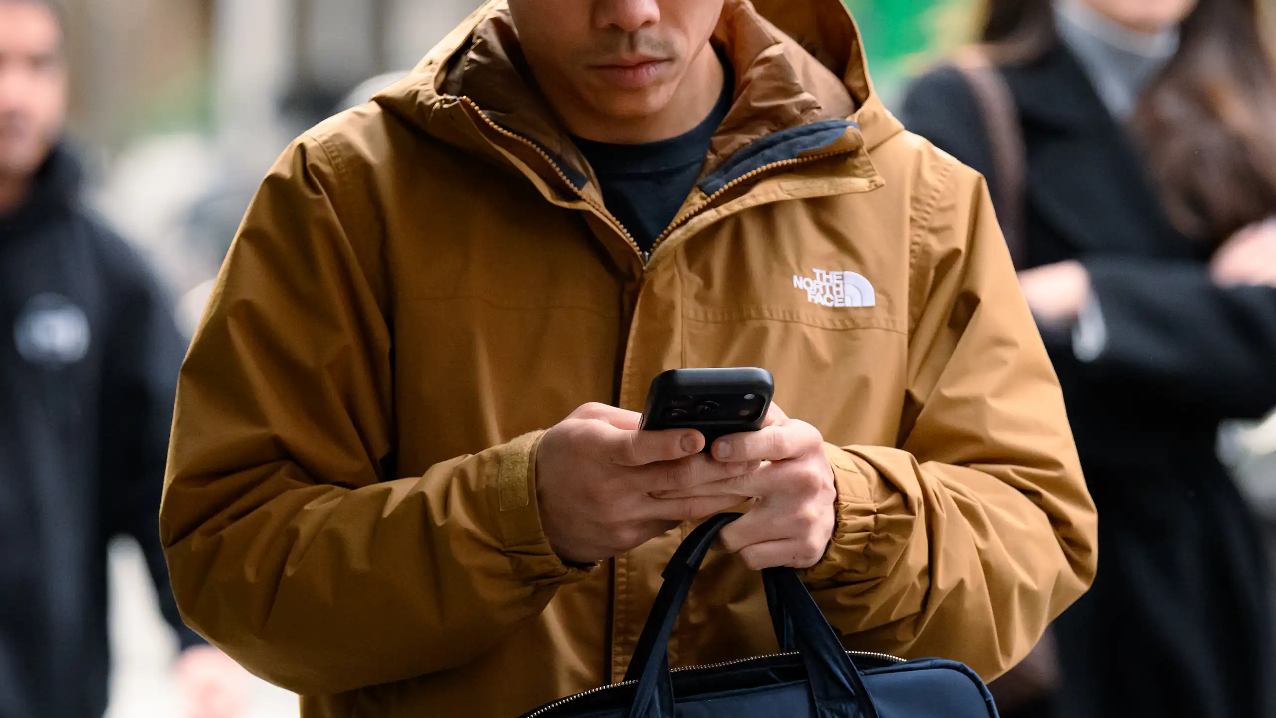 A person walks on the street while holding a phone