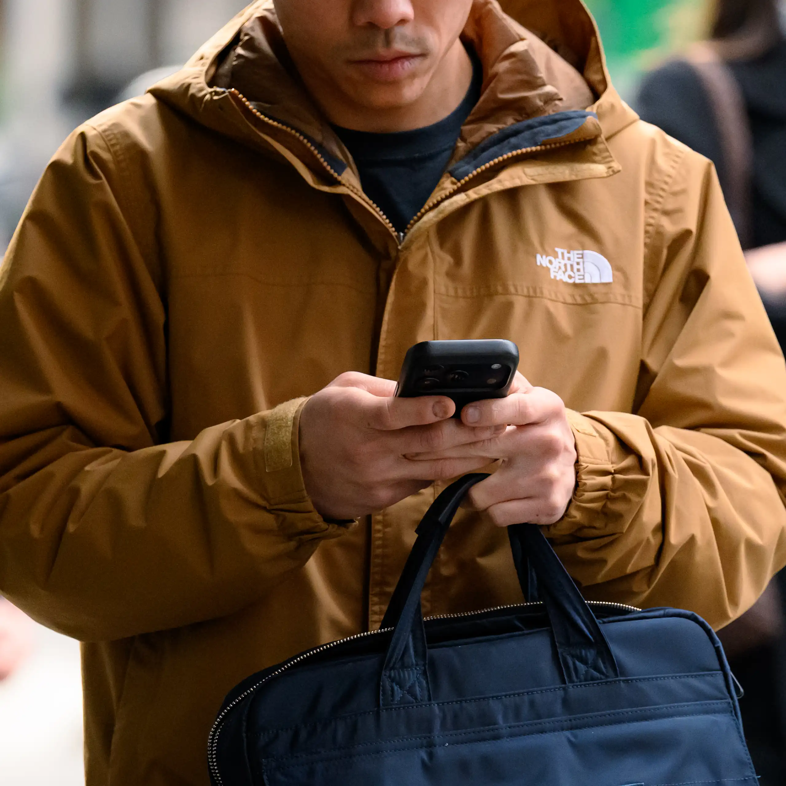 A person walks on the street while holding a phone