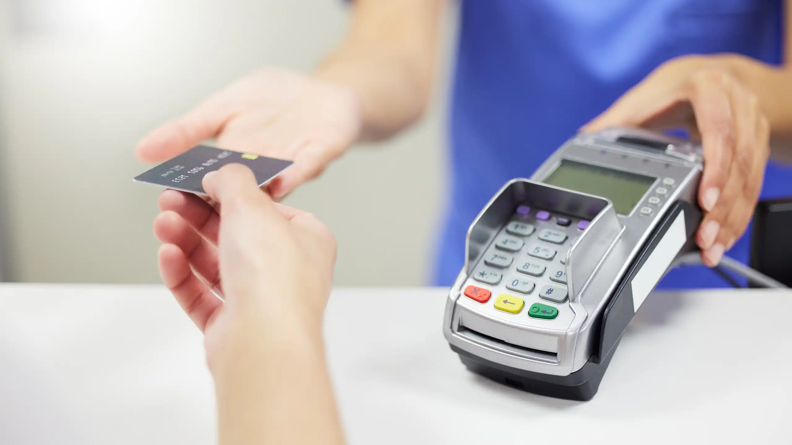 Une soignante tend un terminal de paiement à une patiente pour un règlement par carte bleue.
