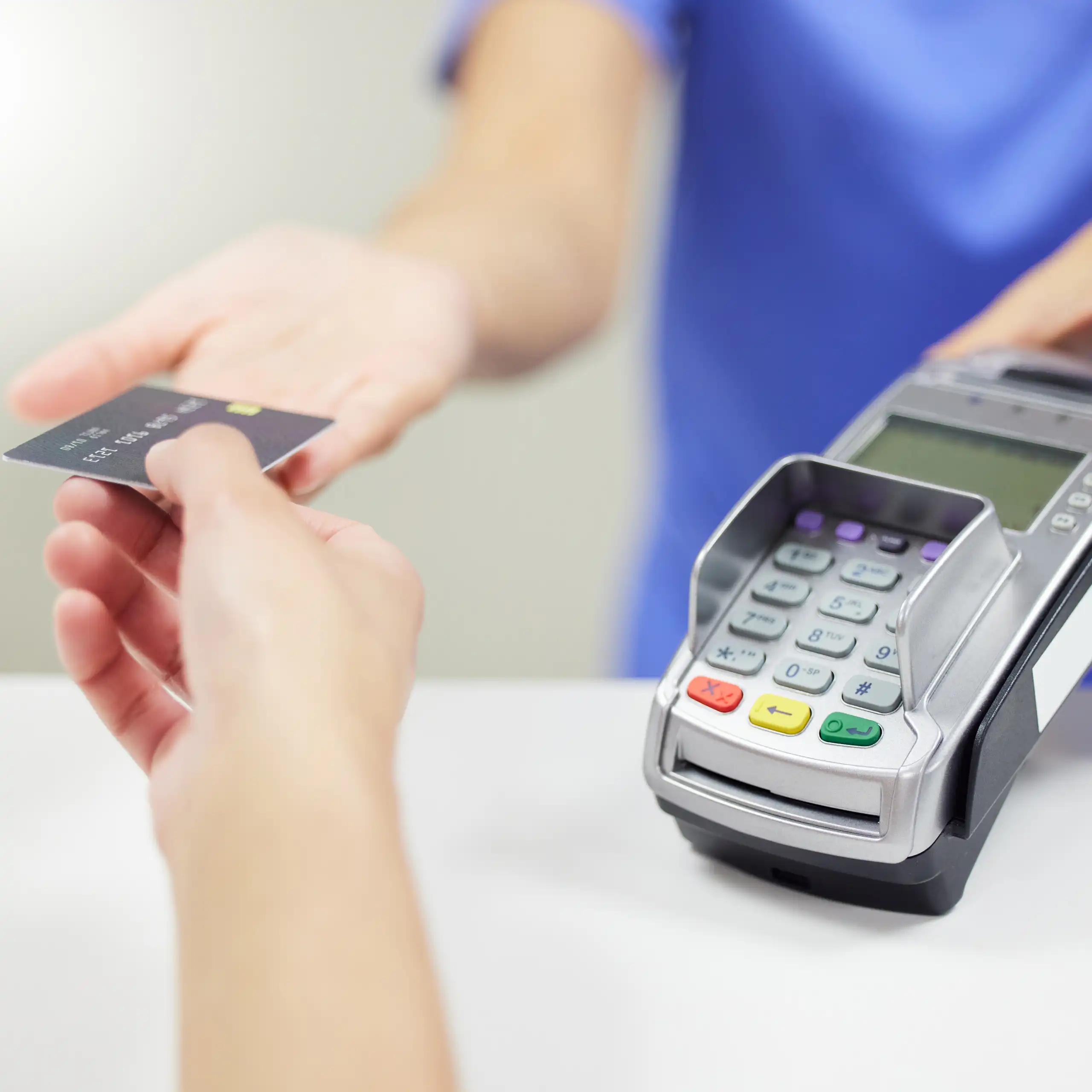 Une soignante tend un terminal de paiement à une patiente pour un règlement par carte bleue.