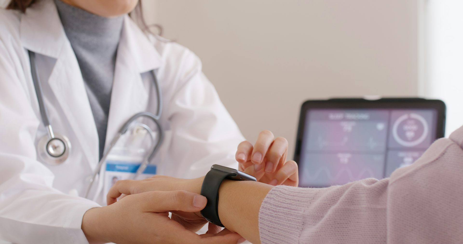 Une soignante manipule une montre connectée au bras d’un patient.