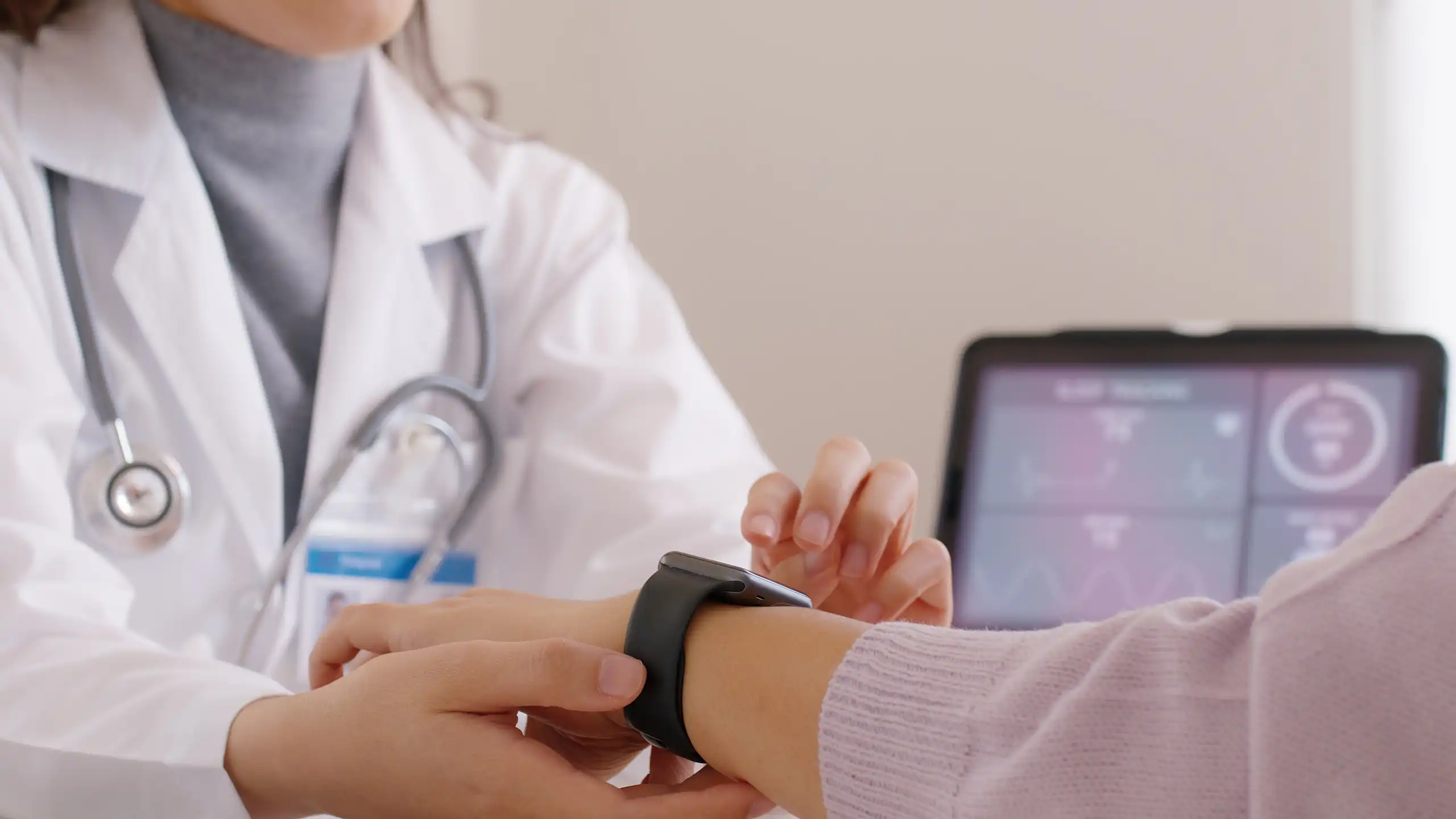 Une soignante manipule une montre connectée au bras d’un patient.