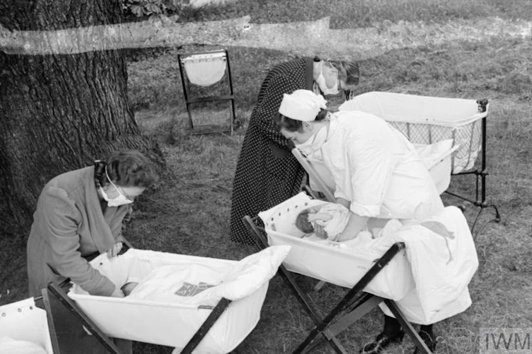 Photographie d'archives montrant des femmes s'occupant de nourrissons dans un jardin.
