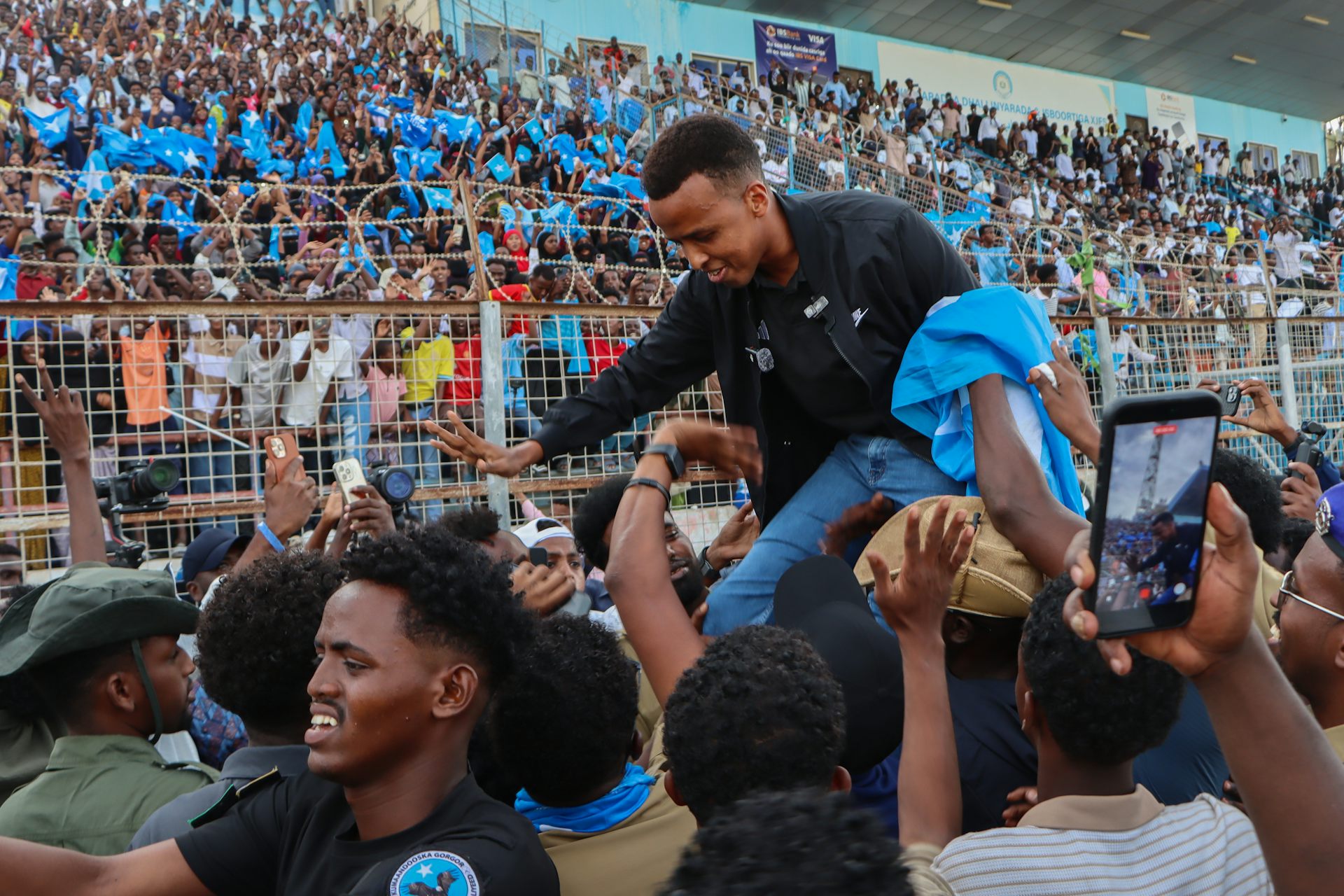 Omar Artan sat on the shoulders of a crowd member as he is welcomed back to Somalia.