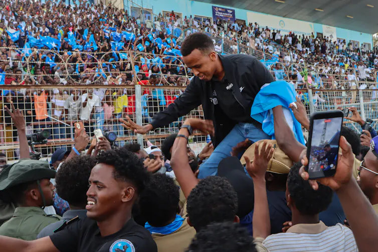 Omar Artan sat on the shoulders of a crowd member as he is welcomed back to Somalia.