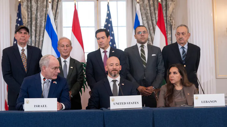 Several people in suits gather at a press conference.