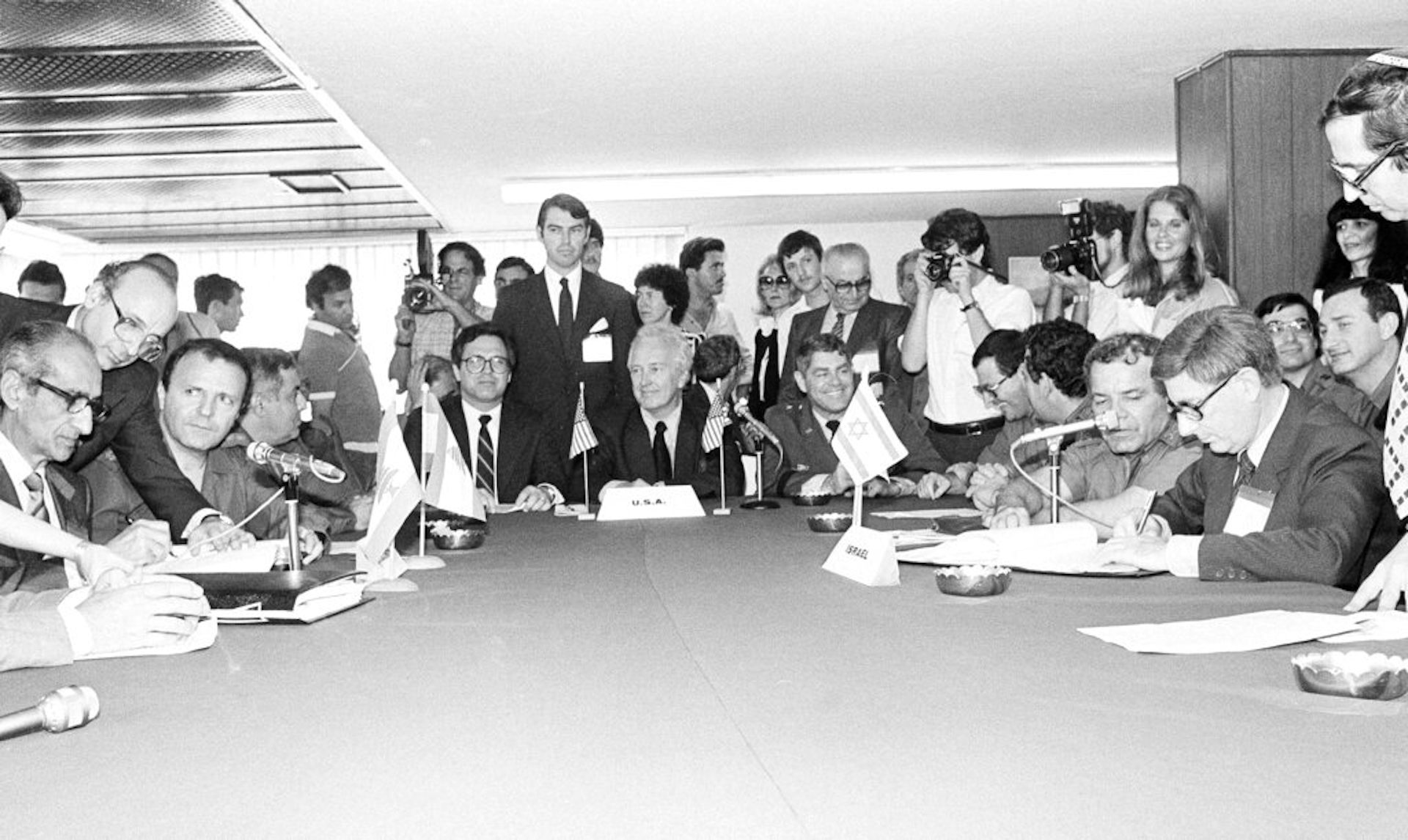 People sit around a conference table in a black and white photo.