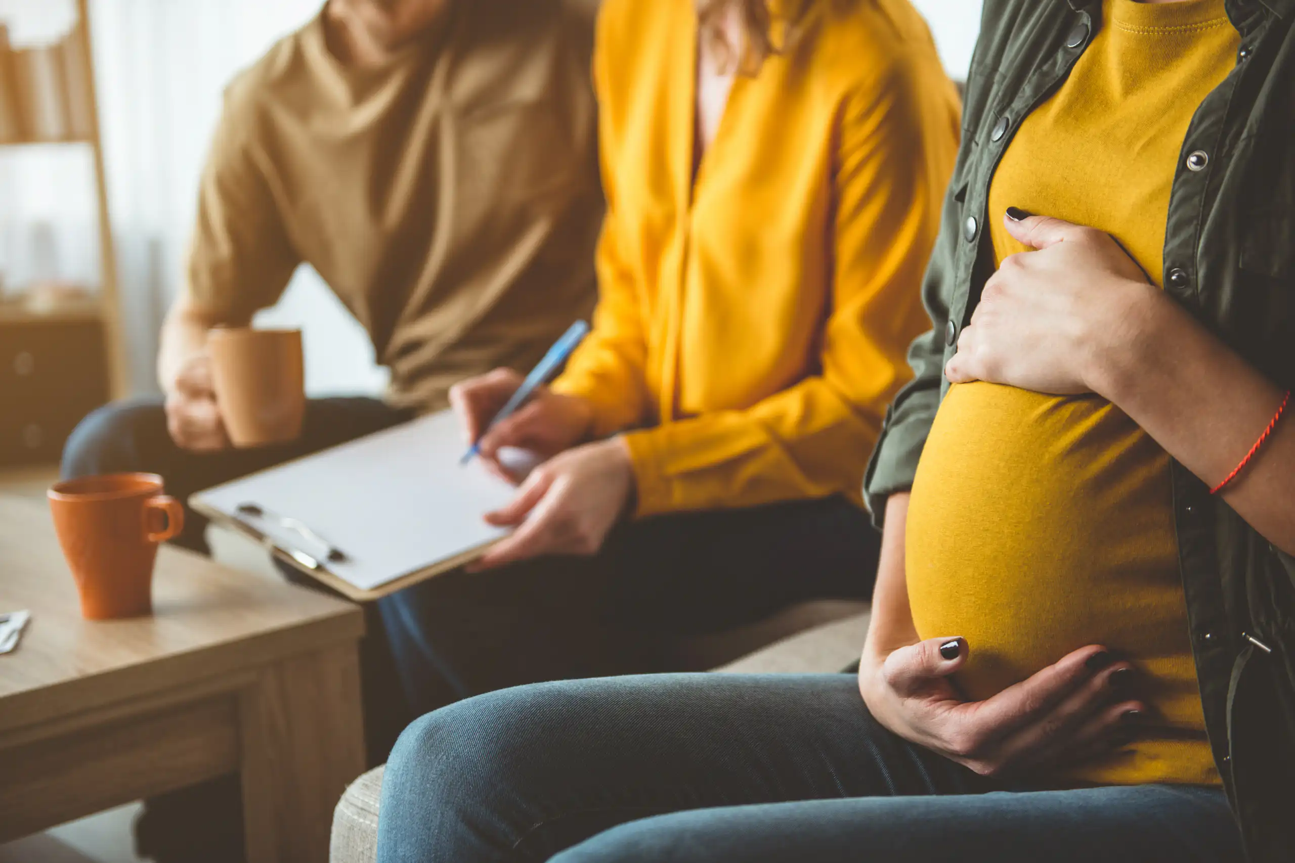 Photo d’une femme enceinte à côté d’un couple.