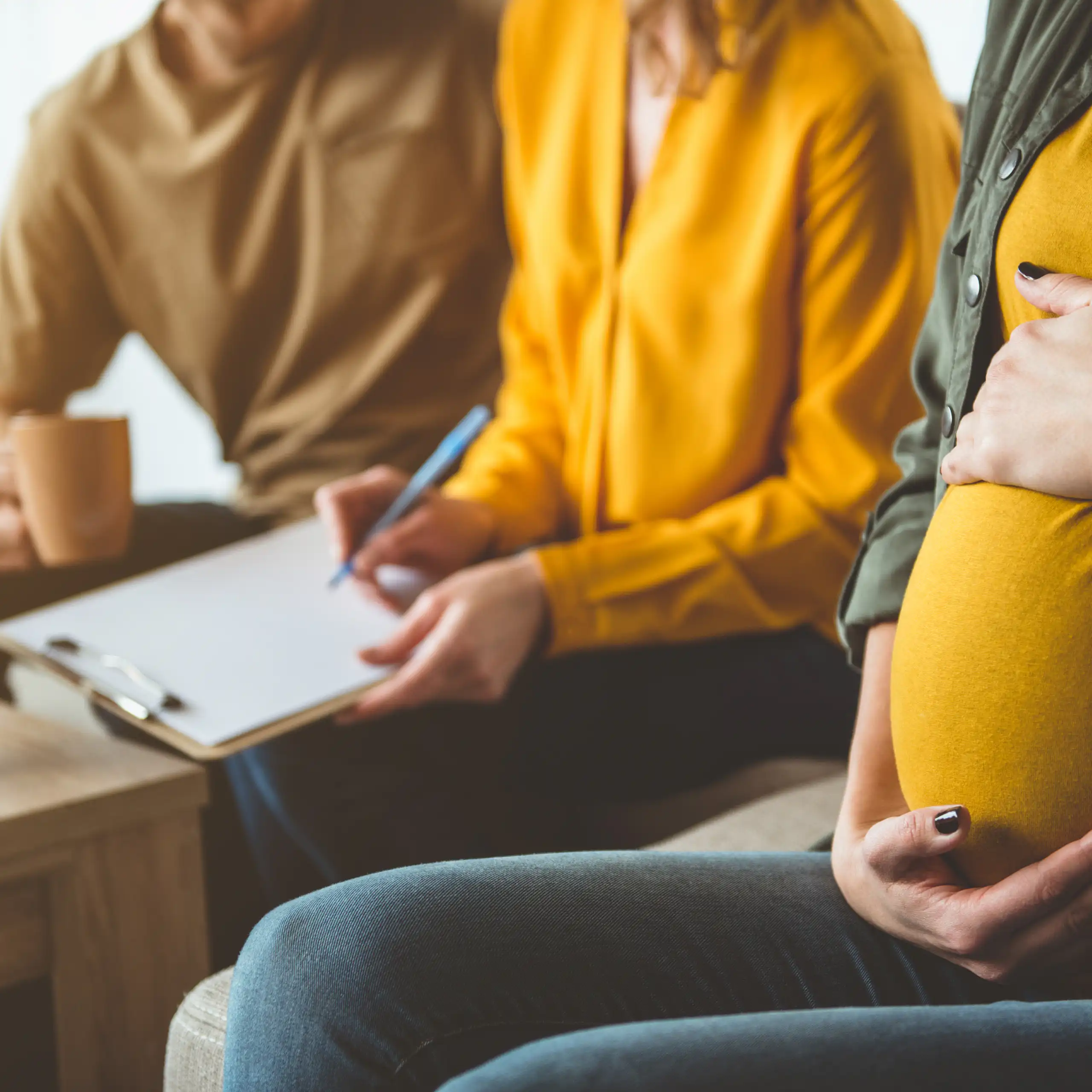 Photo d’une femme enceinte à côté d’un couple.