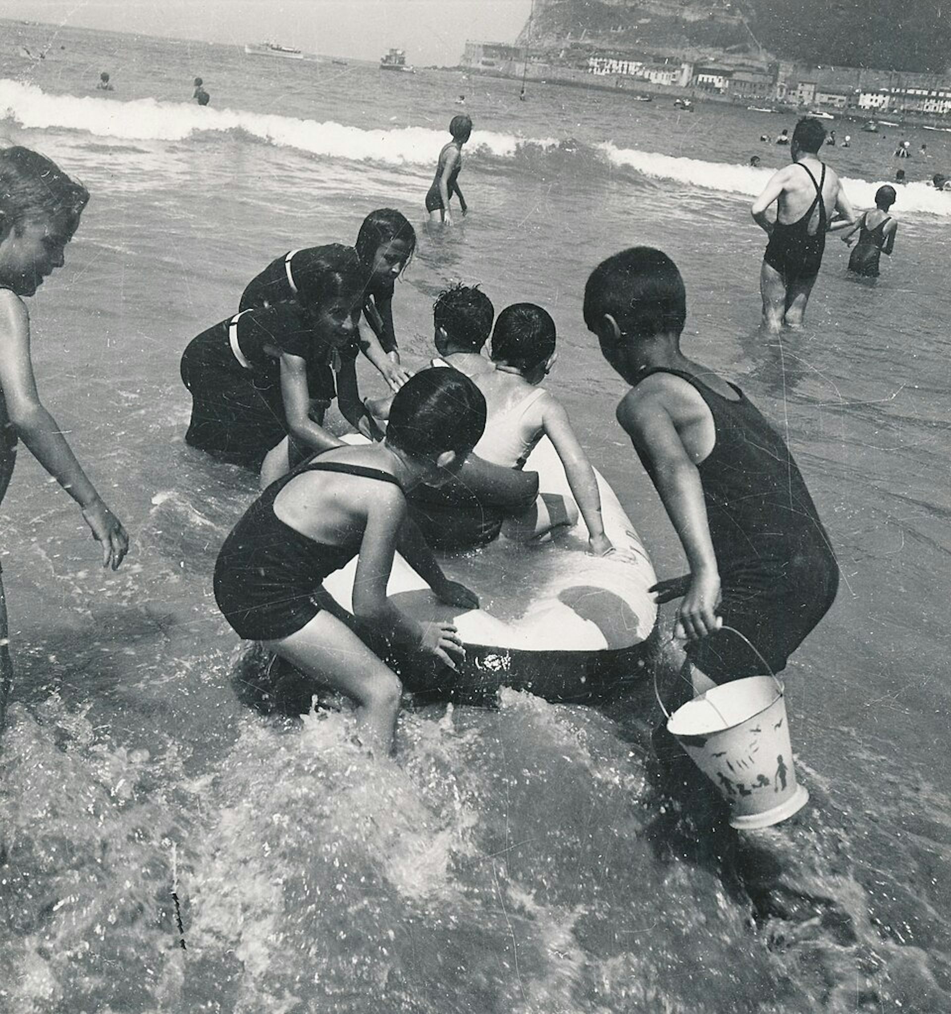 Fotografía en blanco y negro de niños jugando en el agua de mar a principios de la década de 1930.