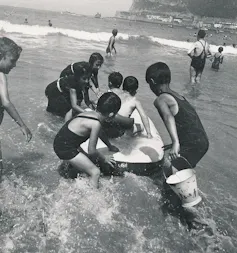 De los baños de mar al turismo de masas: cómo han cambiado las vacaciones en España 1 Fotografía en blanco y negro de niños jugando en el agua de mar a principios de la década de 1930.