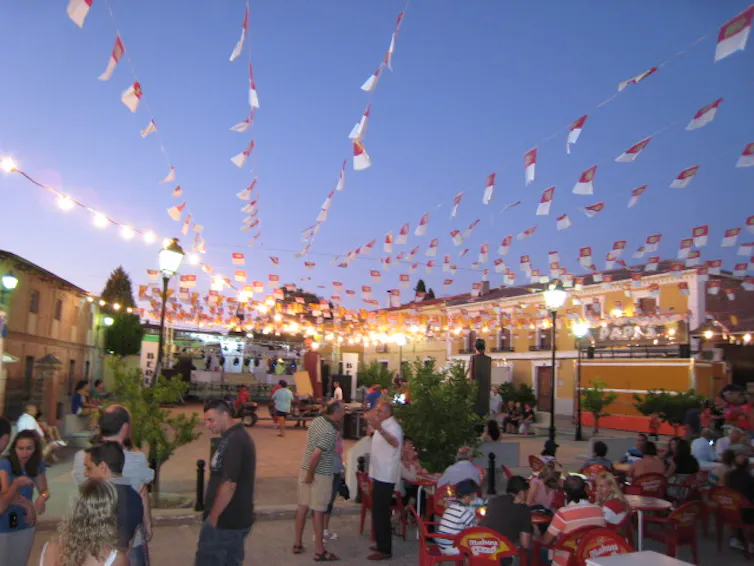 Fotografía difuminada de una plaza del pueblo decorada con banderines para las fiestas.