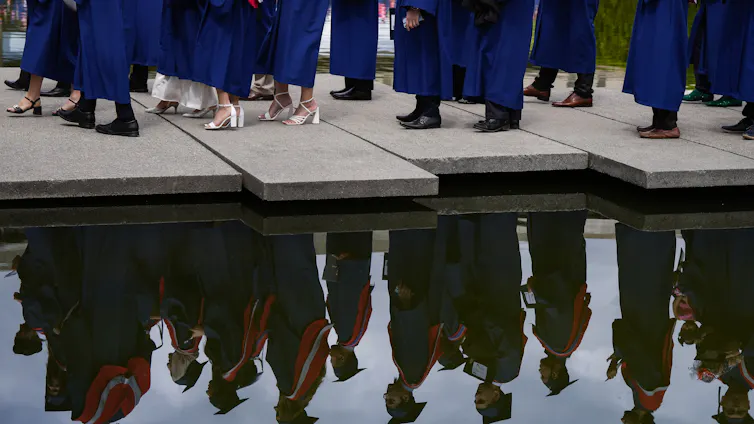Pies de graduados vistos en agua reflectante.