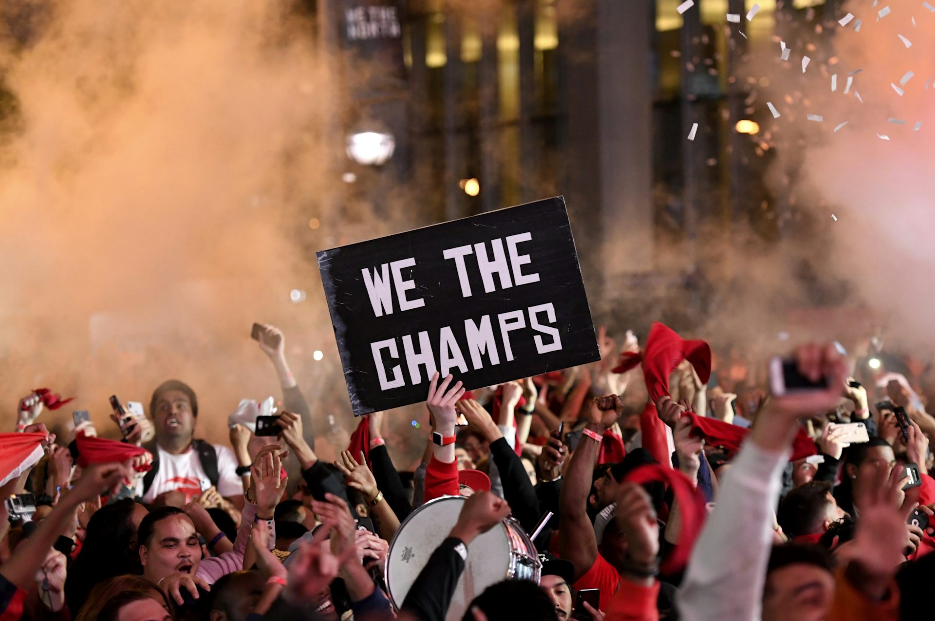 A crowd of people celebrate while holding a sign that says 'We the champs'