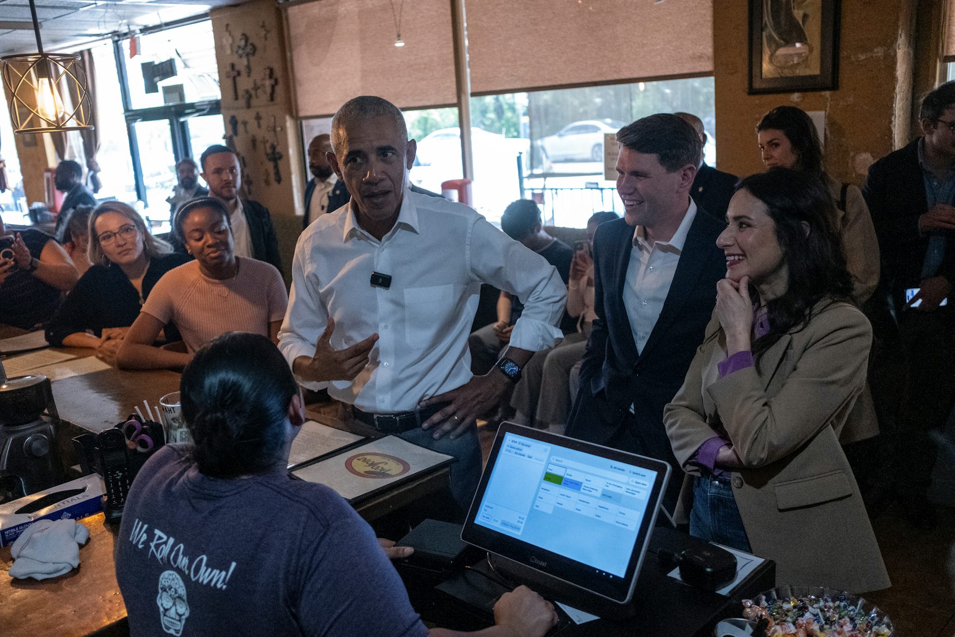 Three people stand at a counter in a taco restaurant
