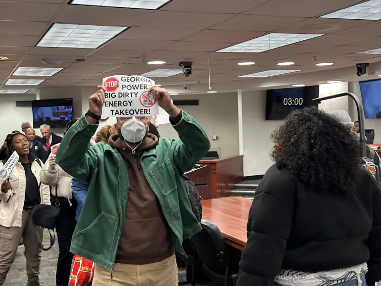 Anti-data center protestors, holding signs, are escorted out of a Georgia Public Service Commission meeting in Atlanta.