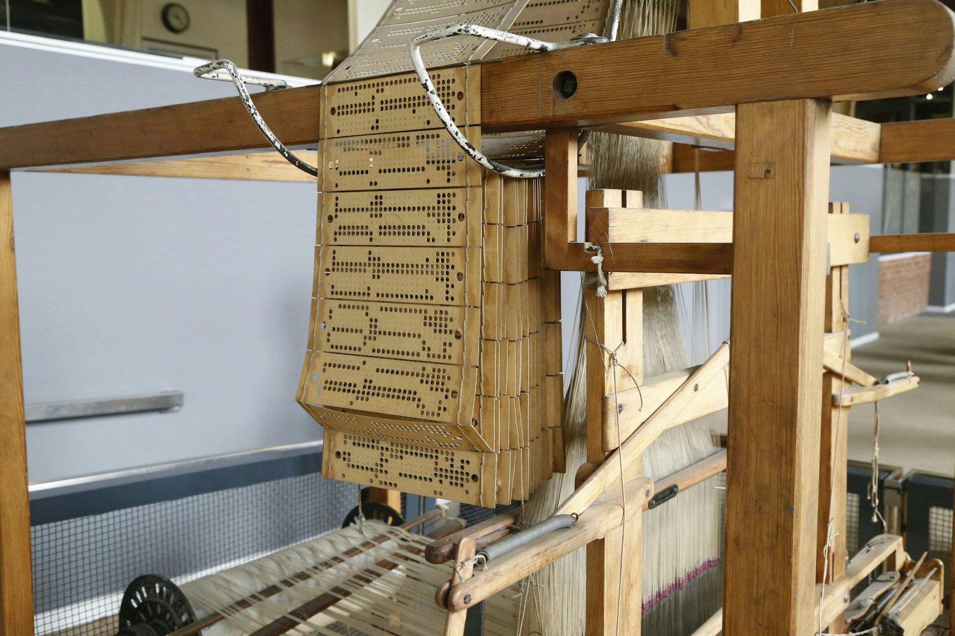 A series of punches of beige cards hang over a wooden apparatus