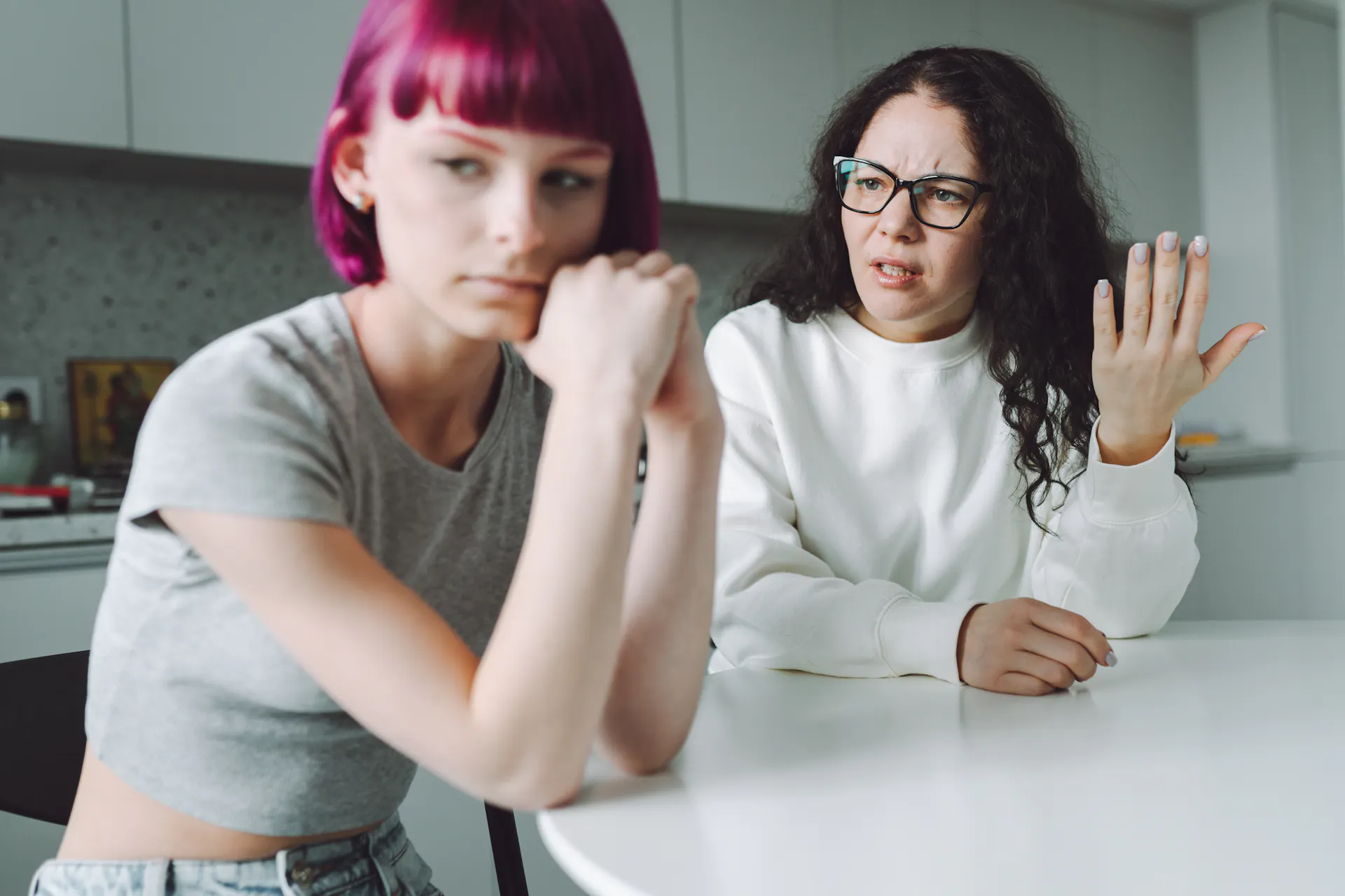 Single working mother and her teenage daughter talk with much emotion in the kitchen.