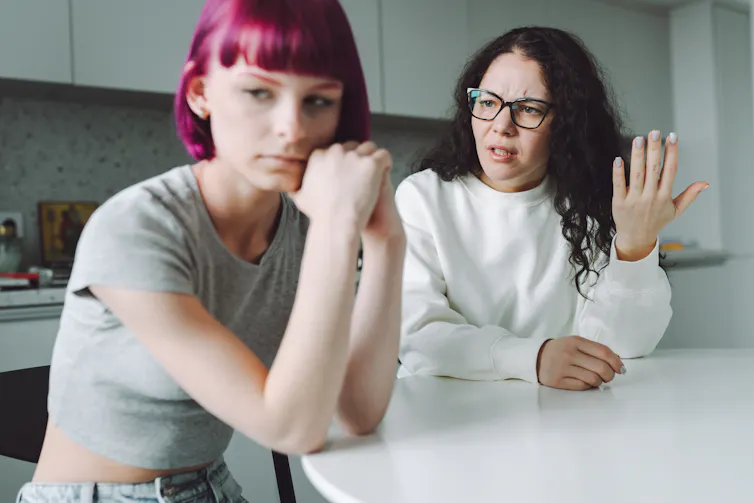 Single working mother and her teenage daughter talk with much emotion in the kitchen.