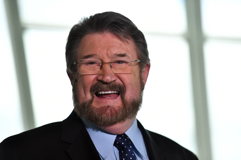 A man with glasses smiles