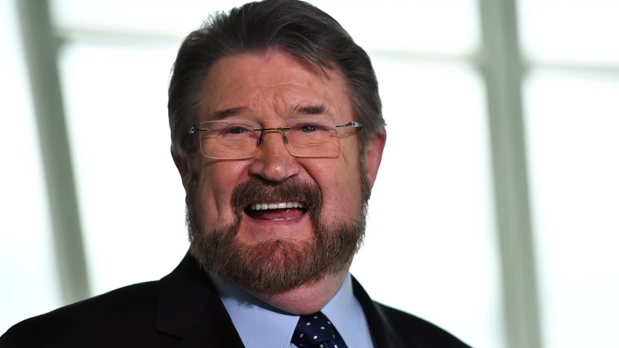 A man with glasses smiles