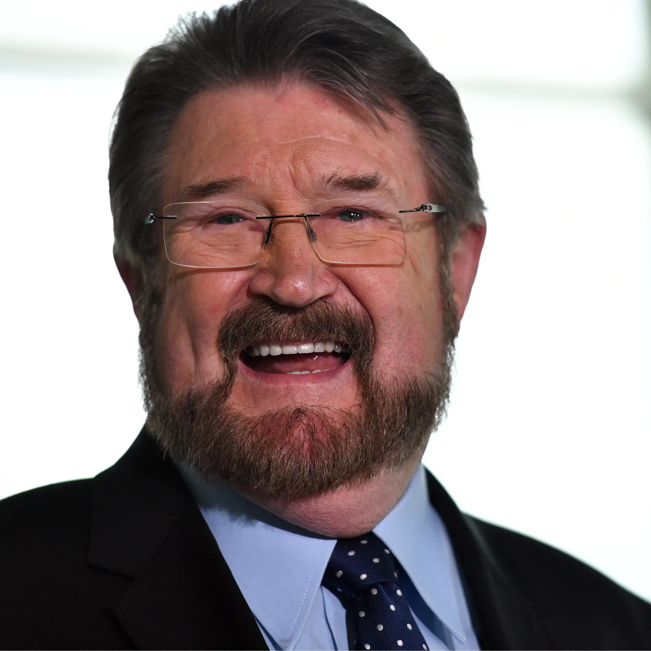 A man with glasses smiles