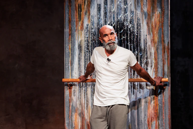 An older Aboriginal man with a grey beard performs onstage.