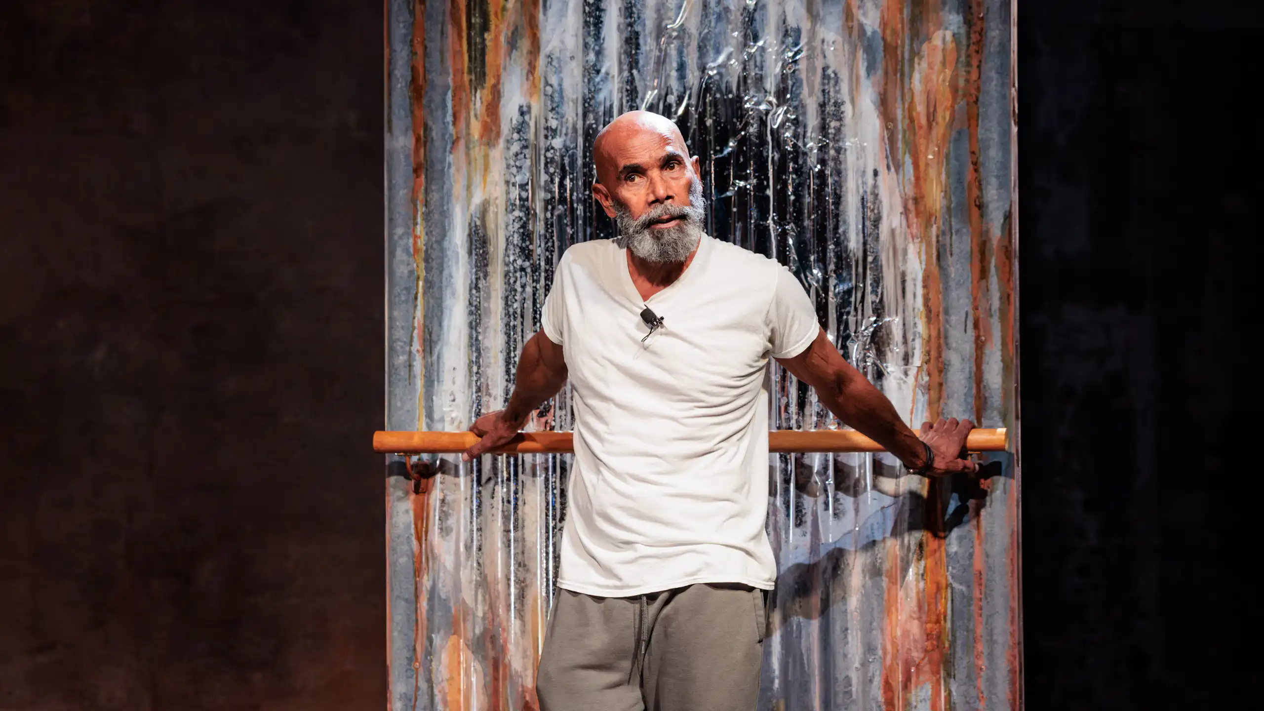 An older Aboriginal man with a grey beard performs onstage.