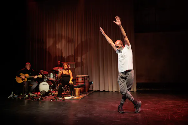 An older Aboriginal man with a grey beard dances energetically onstage.