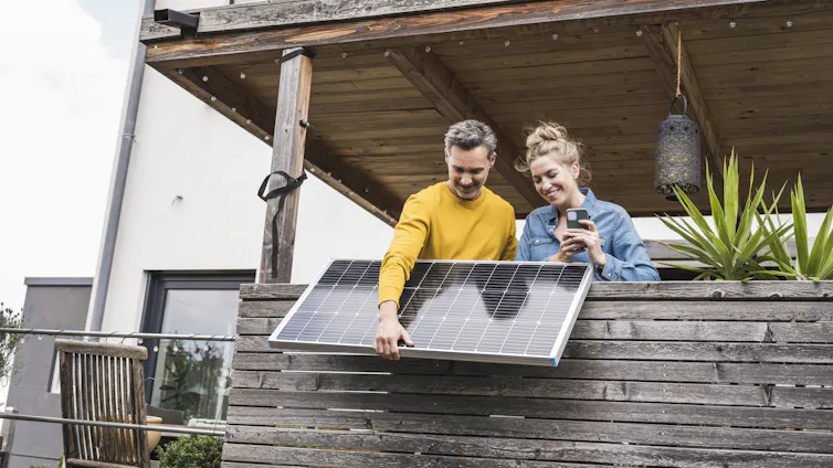 Couple installing a set of solar panels on a balcony.