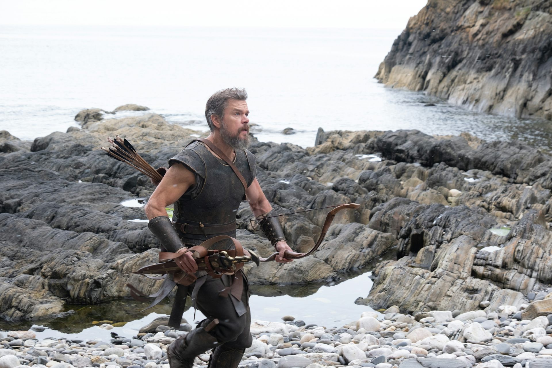 Matt Damon as Odysseus running along a rugged coast