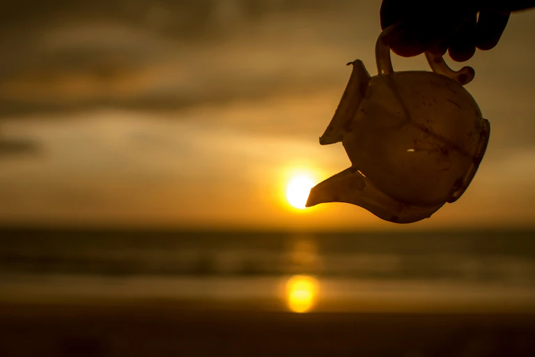 teapot being poured, sunset in background