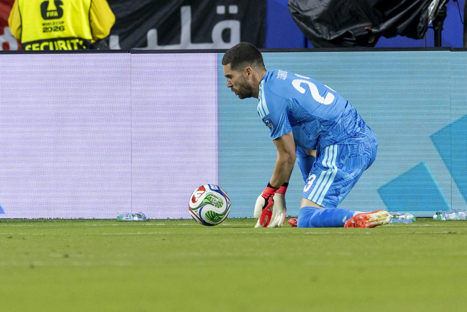 A goalkeeper in blue parries a ball.