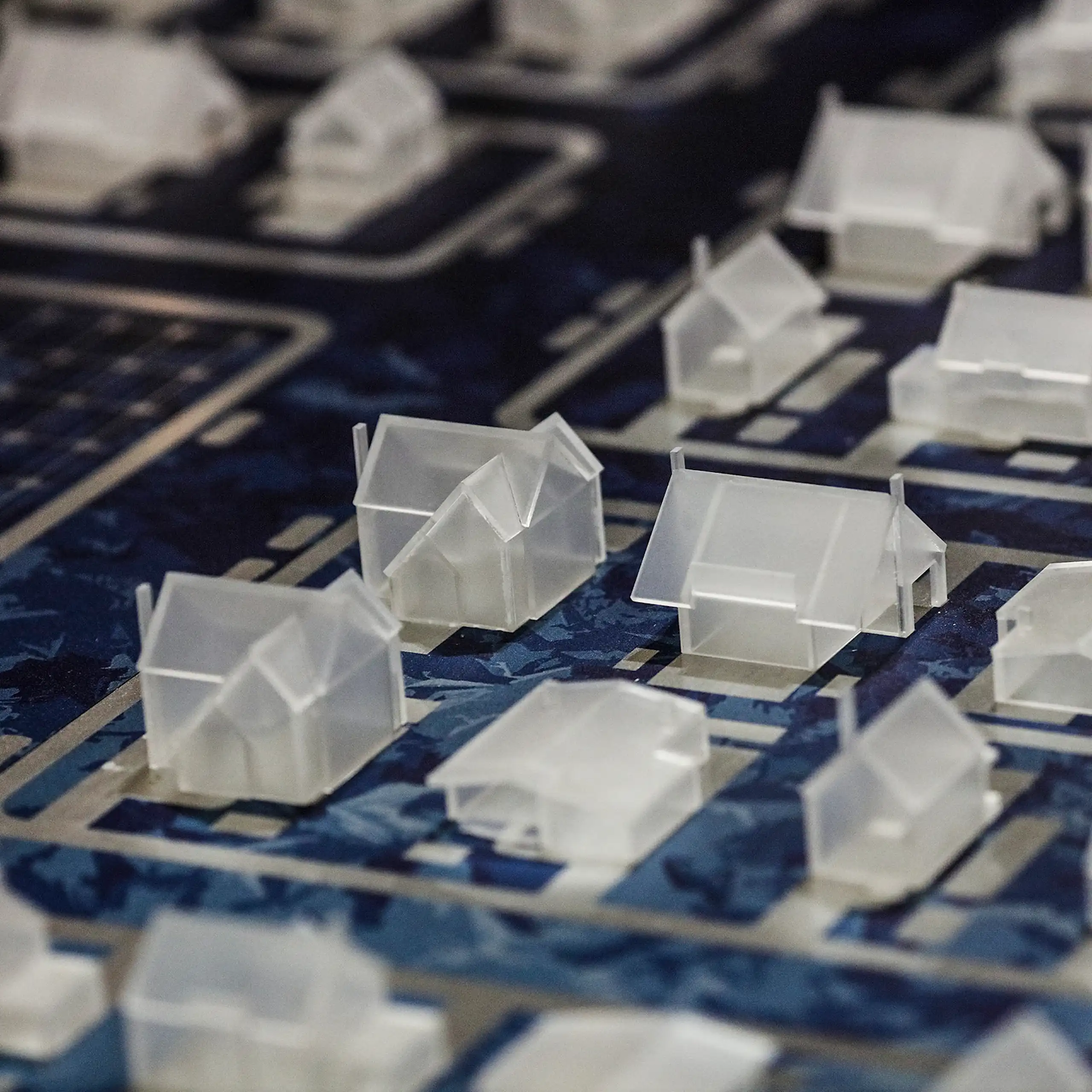Miniature, clear plastic houses laid out side by side in a model of a neighborhood.