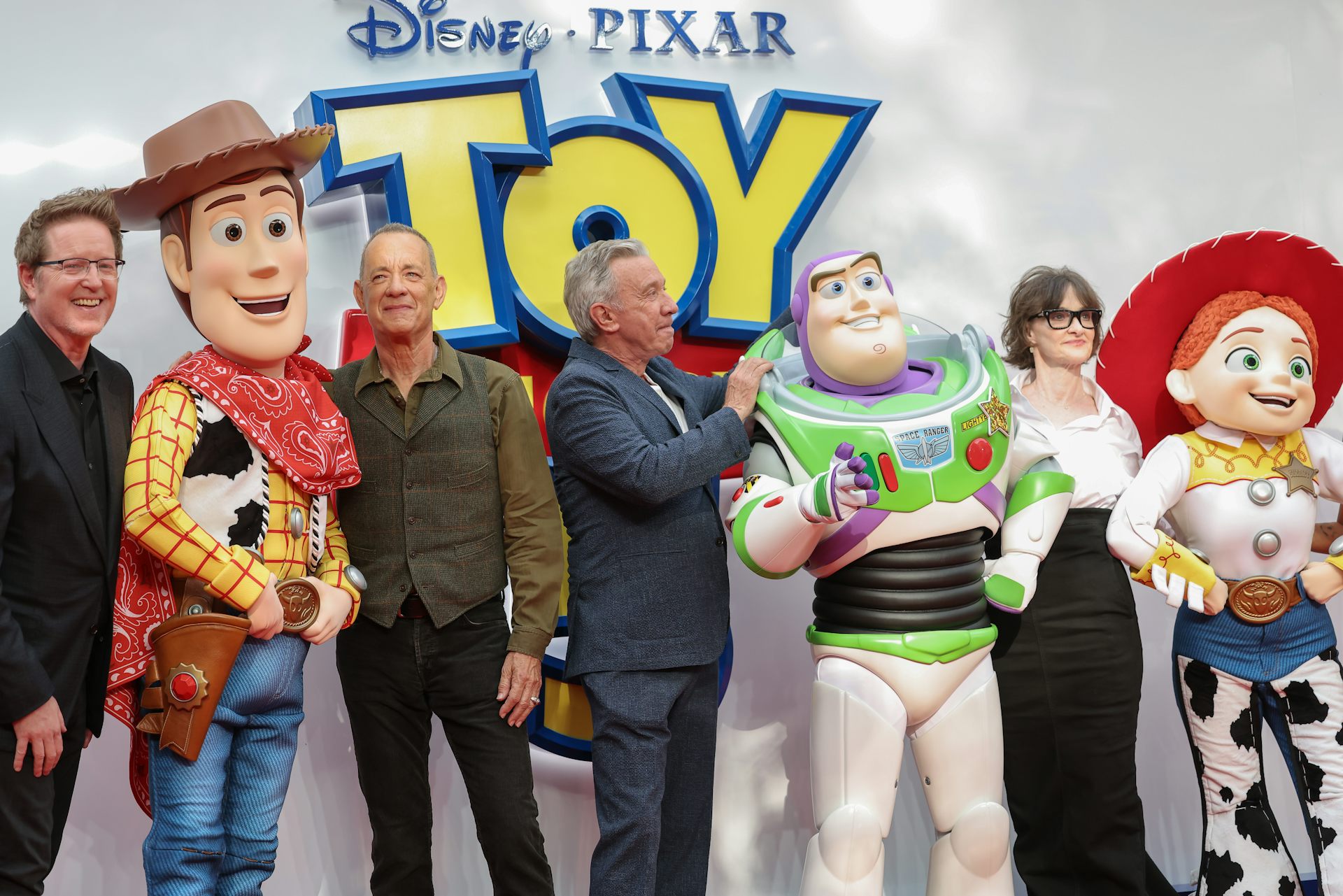 Adults in a row with large cowboy, spaceman and cowgirl characters.