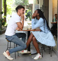 A couple sits at a restaurant patio looking at each other.
