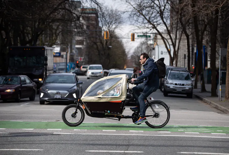 El acceso a la bicicleta es desigual en todas las ciudades canadienses 1 un hombre anda en bicicleta con un niño pequeño y un perro en un compartimento adjunto delante