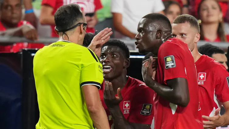 Switzerland's Breel Embolo pleads with the referee after receiving a red card after VAR review.