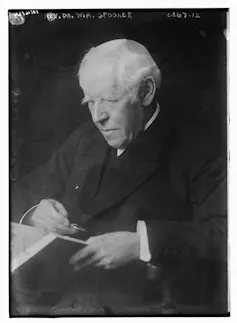 black and white photo of an old man reading a book with a loup