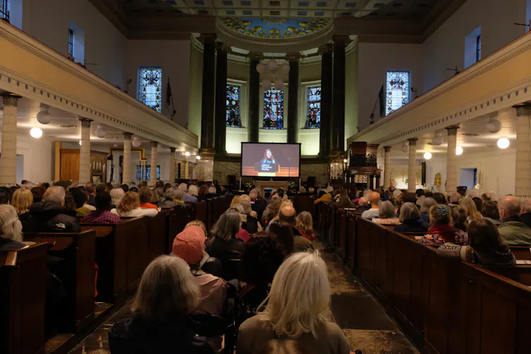 grand inside of building, people sat looking at screen at far end of room