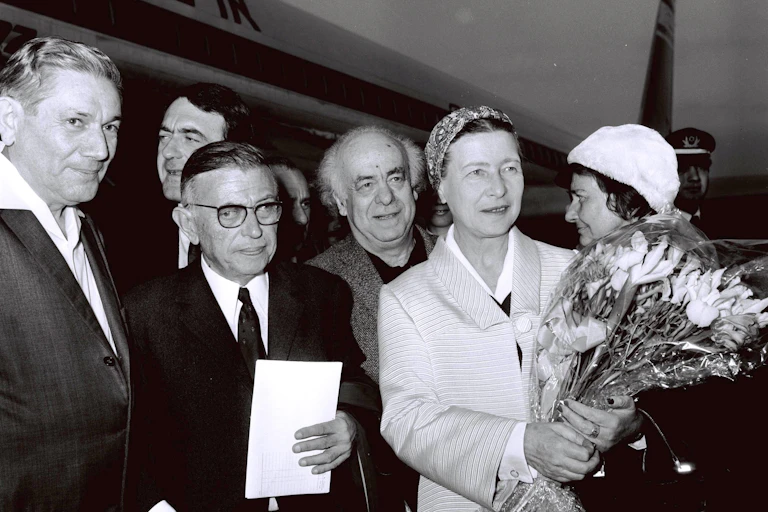 Una mujer sostiene un ramo de flores junto a otros hombres y mujeres en una foto en blanco y negro.