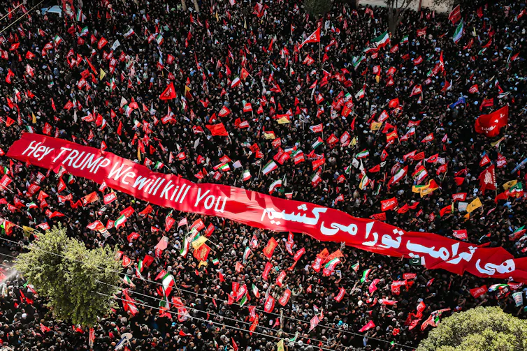 Aerial shot of a crowd in the city of Mashhad displaying a banner reading: 'Hey Trump, we will kill you'.