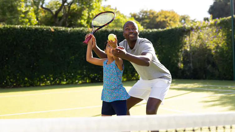 A father and daughter playing tennis together