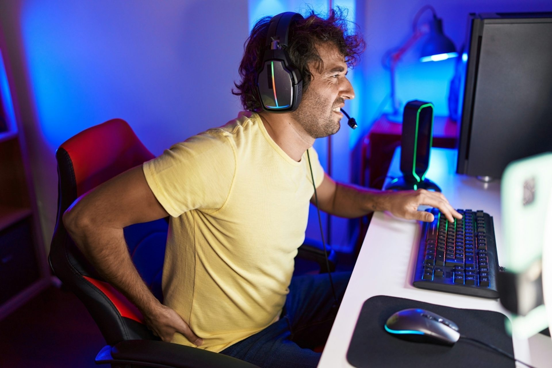 Young man at a computer experiencing lower back pain